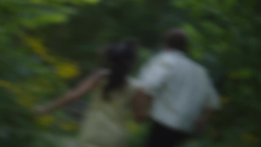 Couple runs hand in hand along a path surrounded by yellow flowers
