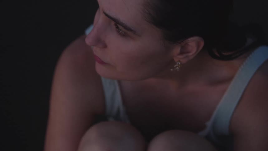 Woman with tied hair looks into the distance with a thoughtful expression