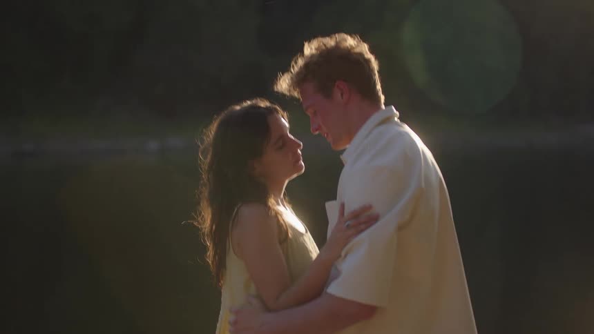 Couple kisses by the water under the gentle light of dusk