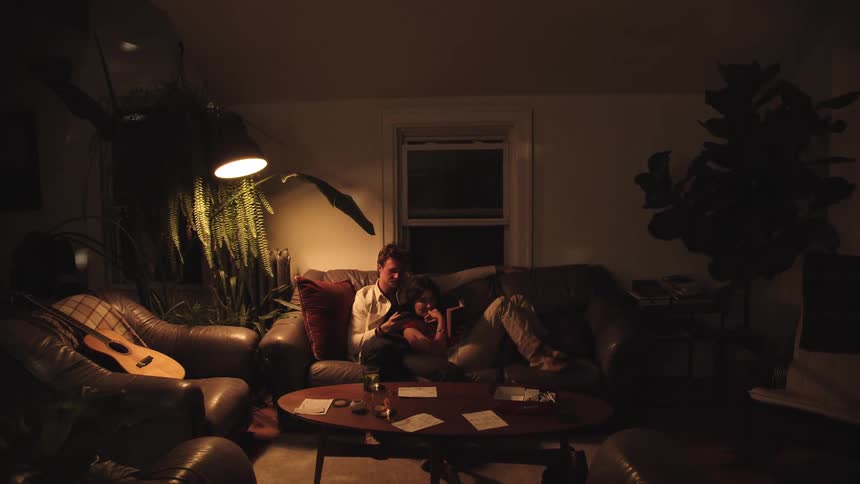 Couple sitting on a cozy living room sofa lit by soft yellow light