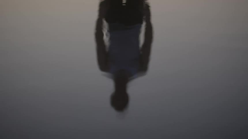 Reflection of a person on the calm water surface at dusk