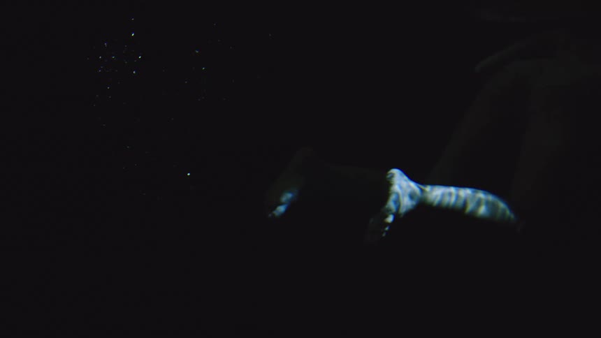 Woman submerged in water with soft lighting highlighting her body