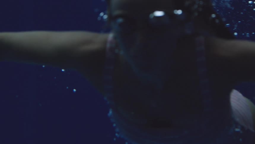 Woman underwater in a pool surrounded by rising air bubbles