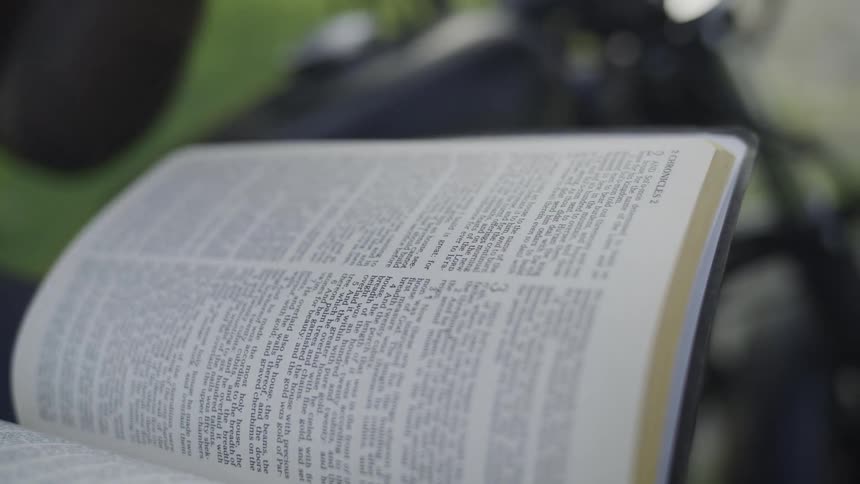 Person holding and reading an open book outdoors