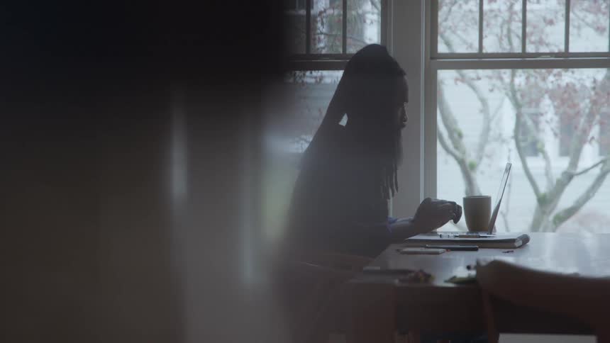 Man works on a laptop at the table near the window