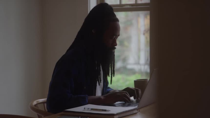 Man works focused on a laptop near the window