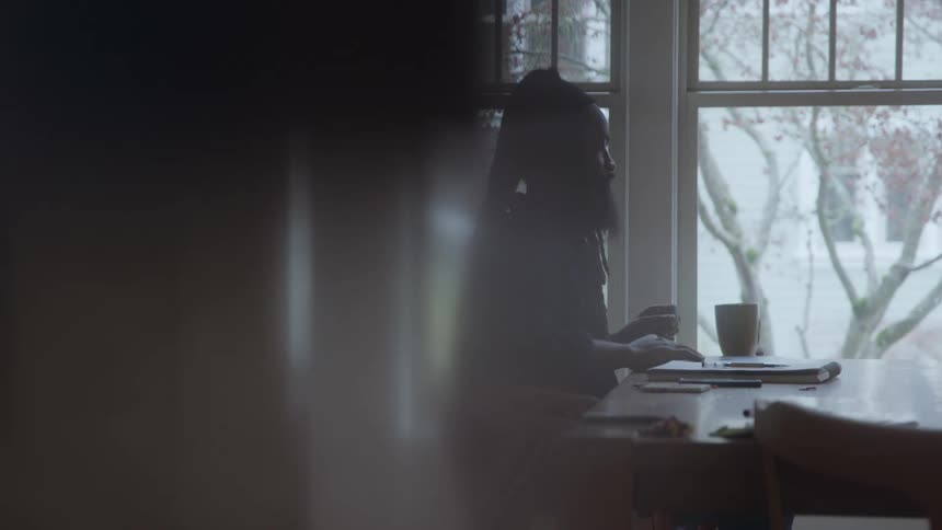 Man sits at the table with hands clasped before his face in reflection