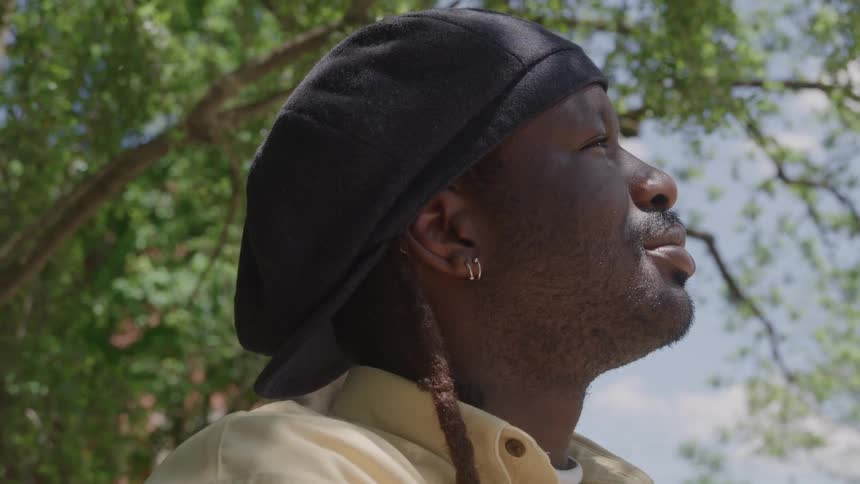 Man wearing a black beret smiles softly while enjoying the day outdoors