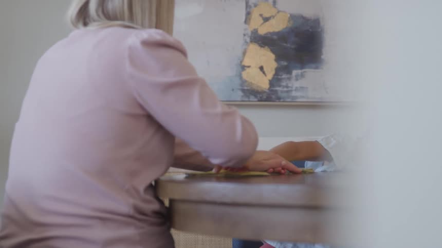 Mother and daughter play happily at the table in a bright room