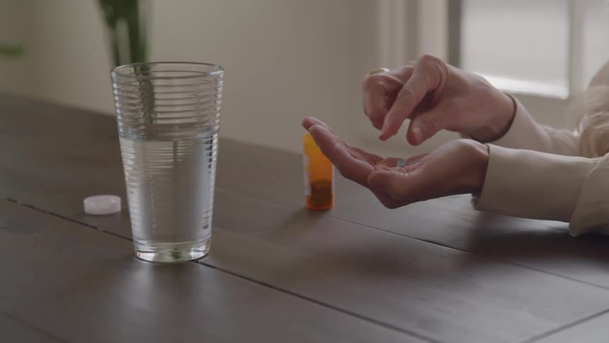 Hand holds orange pill bottle