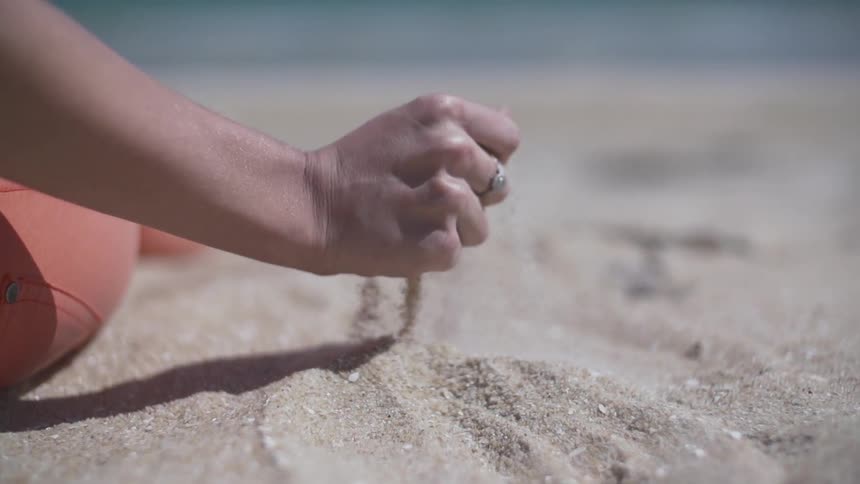 Person traces their hand through some sand