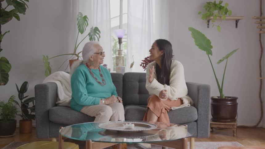 Two woman talking on a couch in a bright living room