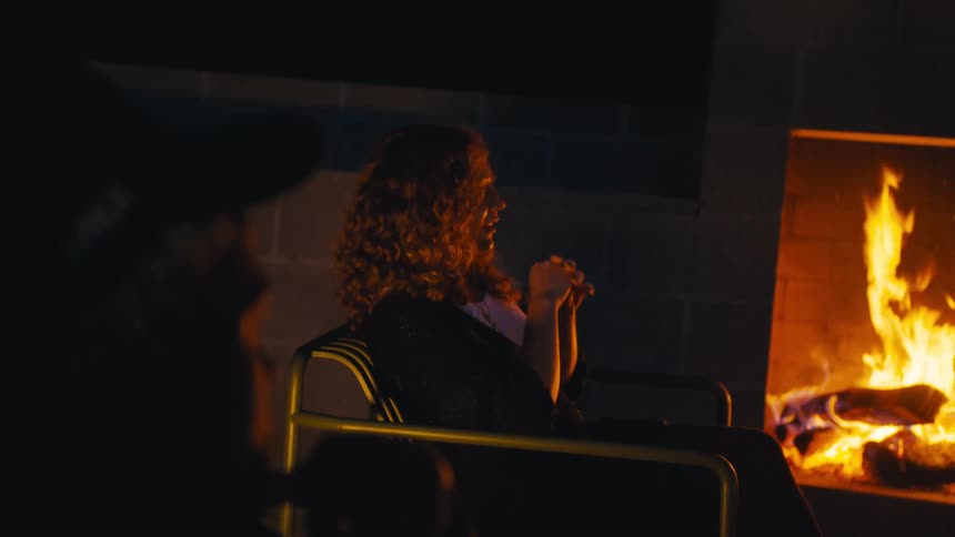 The woman is talking by the fireplace