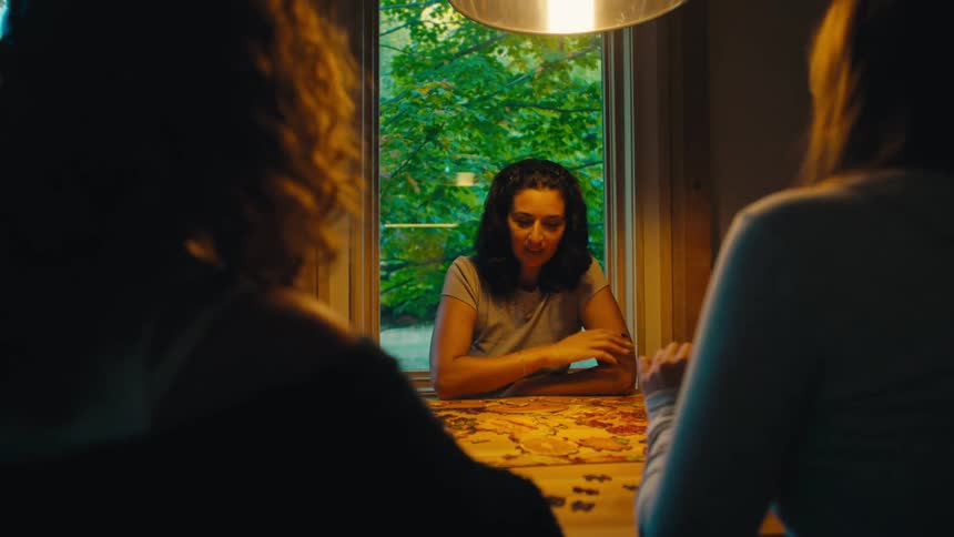 Three people gathered around a table assembling a puzzle under warm light