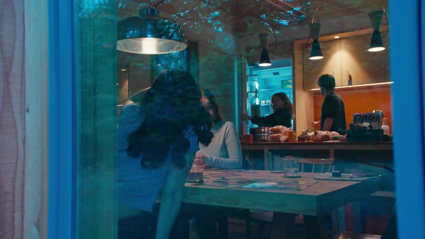 Group gathered in cozy kitchen with tree reflections on window and atmosphere of social interaction