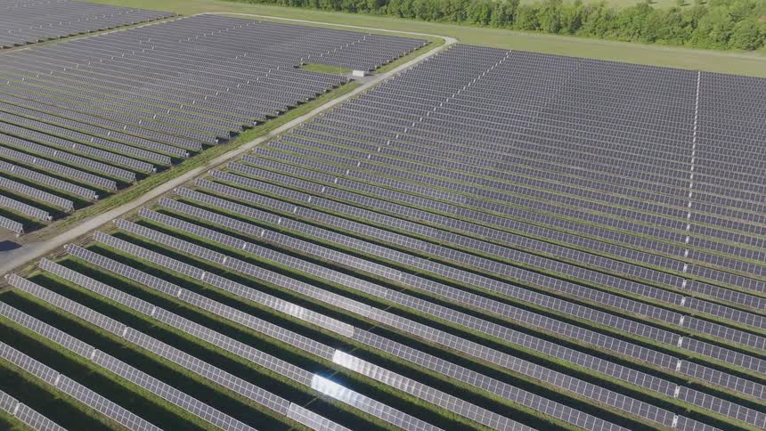 Aerial view of a solar farm with rows of panels across an industrial landscape