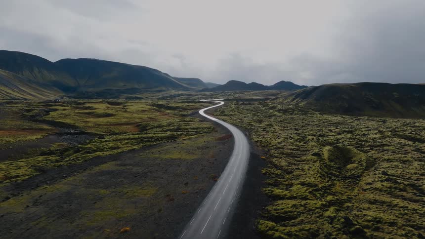 Winding road cuts through a mountainous landscape covered with green vegetation