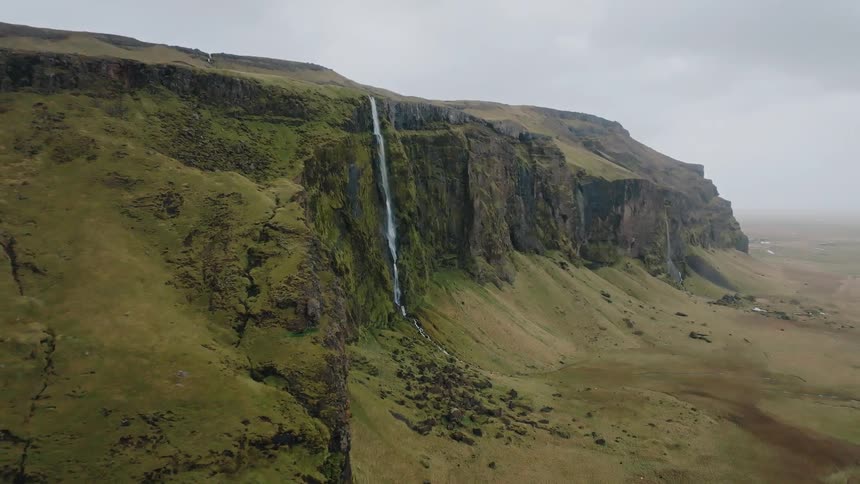 Narrow waterfall cascading down a mosscovered cliff
