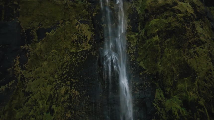 Aerial of a waterfall flowing down a steep slope in the canyon