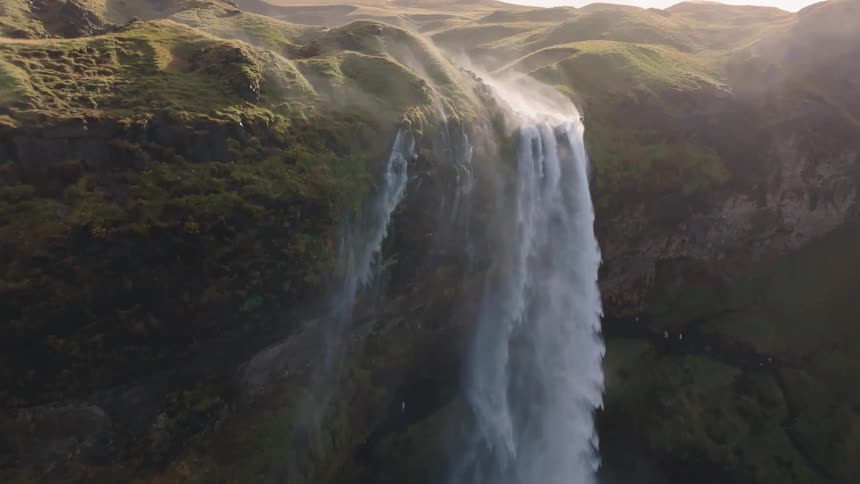Aerial of waterfalls flowing rapidly into a river through the canyon
