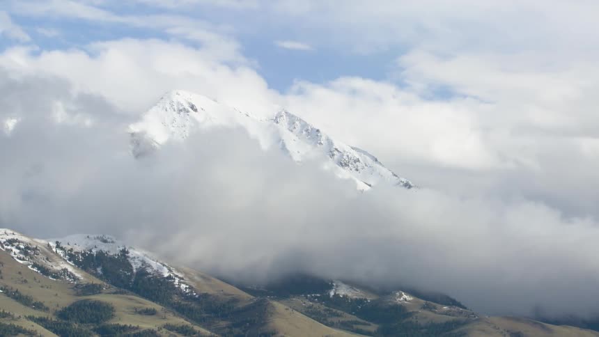 Snowcovered mountain partially enveloped by dense clouds