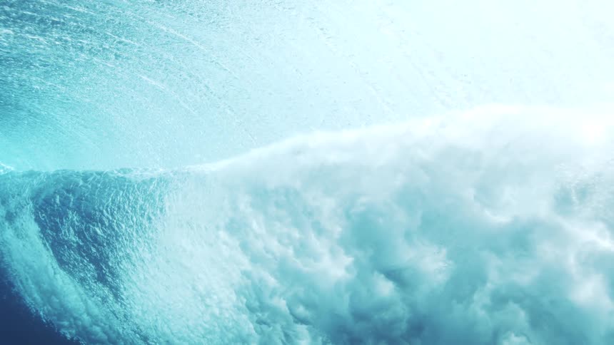 Waves seen underwater forming swirls of blue foam