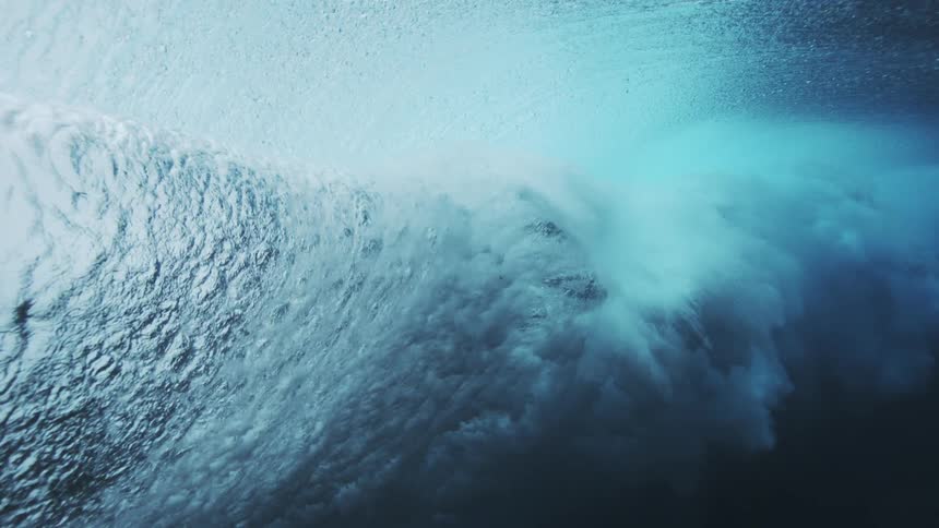Underwater wave curves in motion forming a translucent tube filled with bubbles