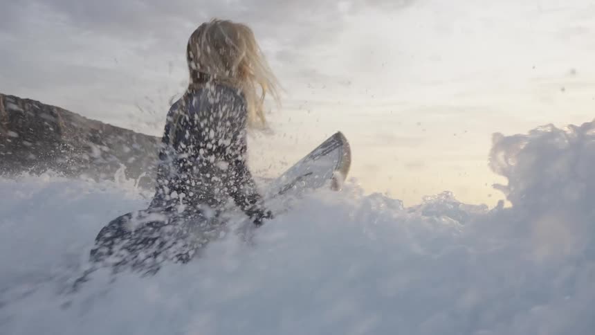 Surfer watching the waves while holding the board in the sea