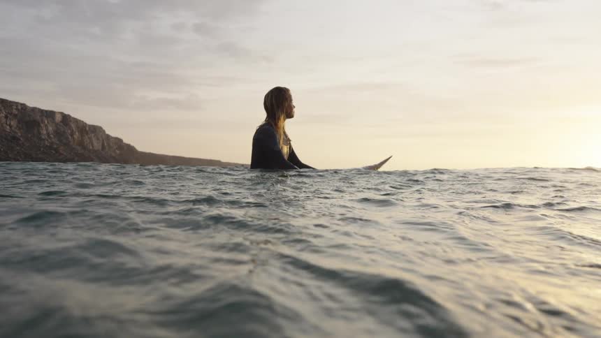 Surfer gazes at the horizon during sunset in the sea
