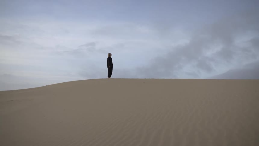 The woman turns in a circle on the dune