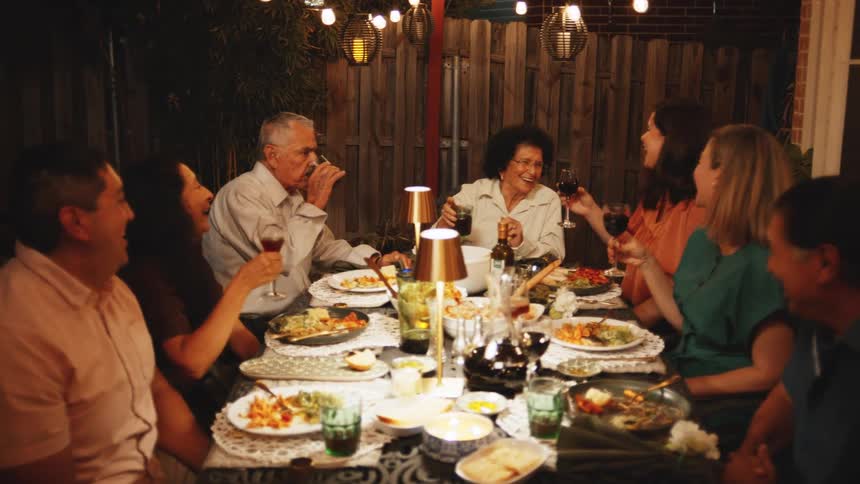 Family laughs and talks during a meal outdoor