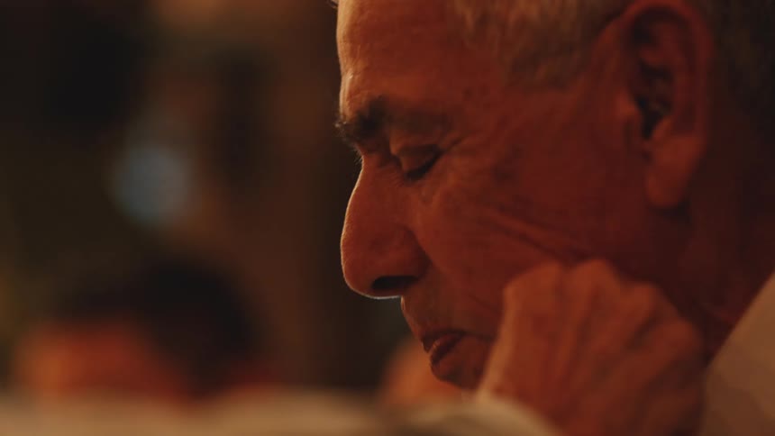 Elderly man chewing thoughtfully in a warmly lit setting
