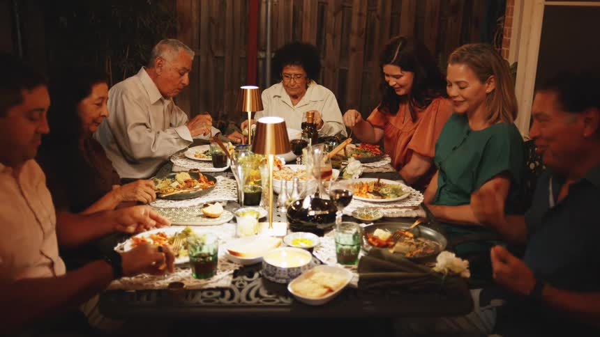 Group gathered around rectangular table sharing a meal in a cozy setting