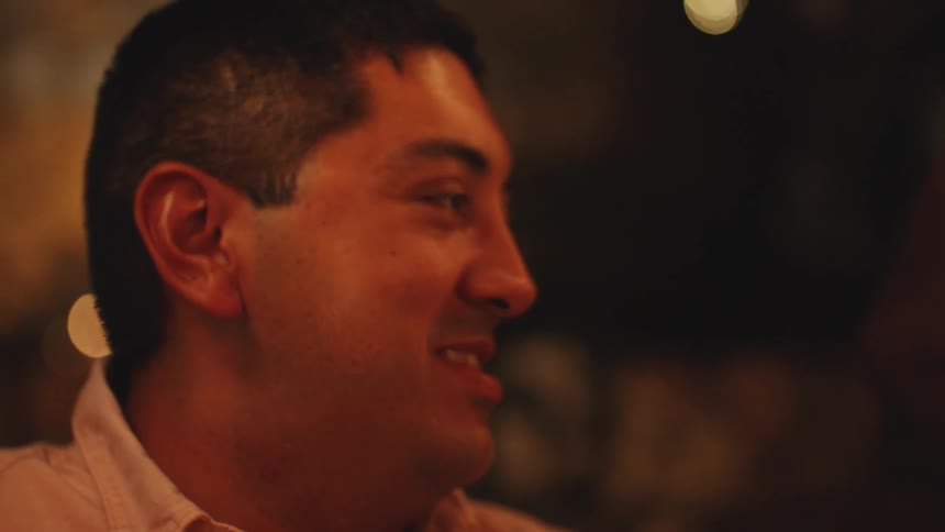 Man smiles in an indoor setting with warm soft lighting