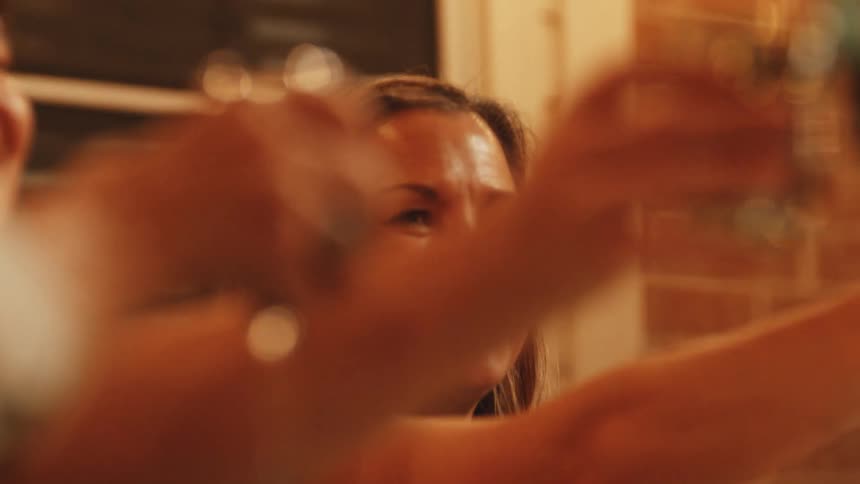A closeup shot captures people cheerfully toasting with drinks indoors