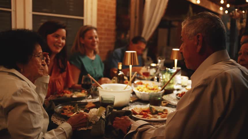 A multigenerational group dines and talks at a restaurant table