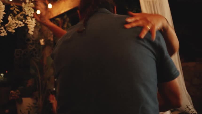 Couple smiles while dancing in a warmly lit setting