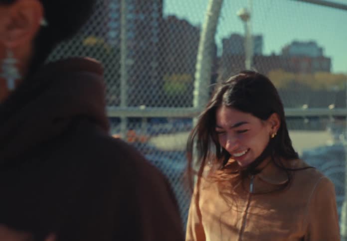 College friends both male and female walk along the sidewalk laughing together under the bright sun