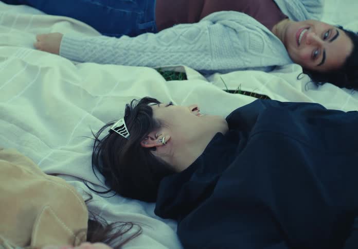 Young woman lies on a bed smiling with friends nearby