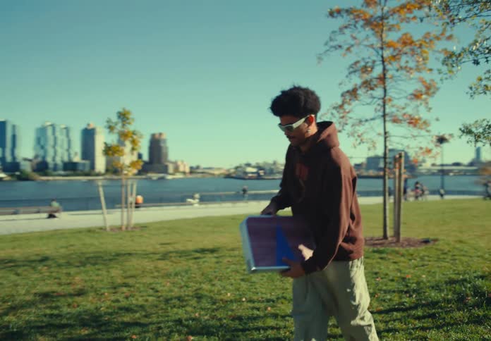 Man sets up a game on the lawn of a park overlooking the river and buildings in the background