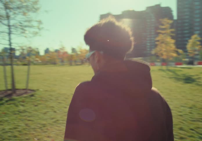 The video begins with a closeup of a folding picnic table being removed from a teal wagon full of supplies on a grassy field the camera then follows a man wearing sunglasses and a brown hoodie carrying the table as he walks toward a scenic wate