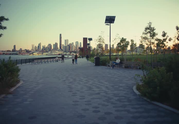 People walking along waterfront promenade with city skyline