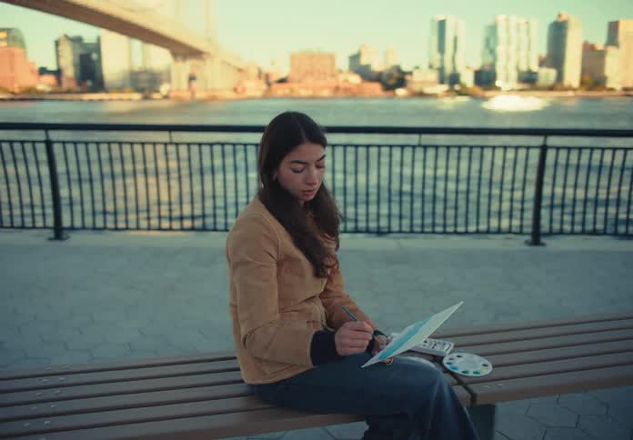 A woman paints while sitting on a bench