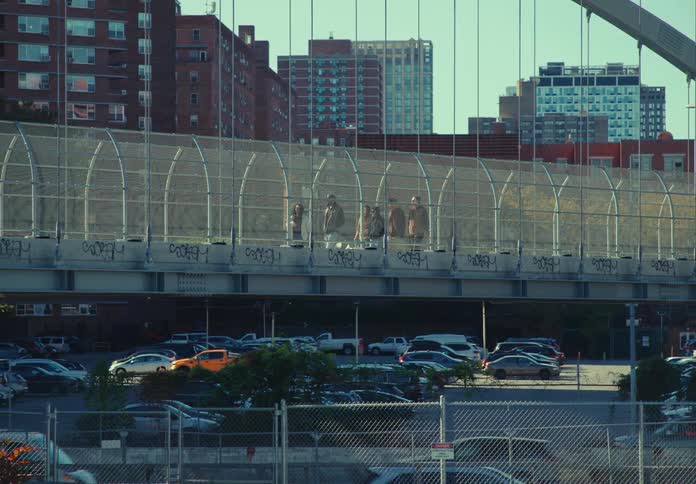 Group of people crossing a fenced pedestrian bridge in an urban area