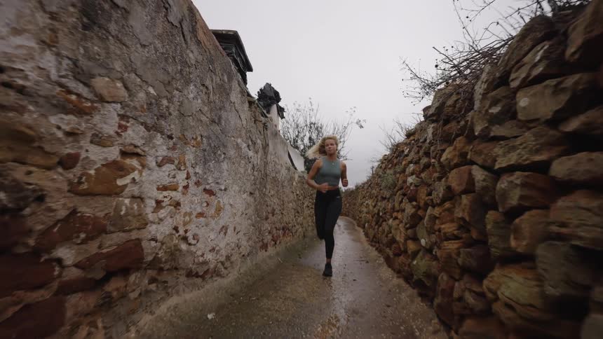 Woman runs through a narrow rocky alley
