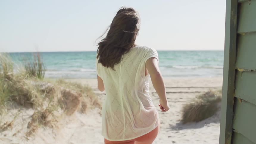 Woman jogs towards the ocean