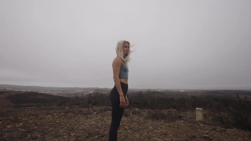 Woman walking on a hillside under a cloudy sky