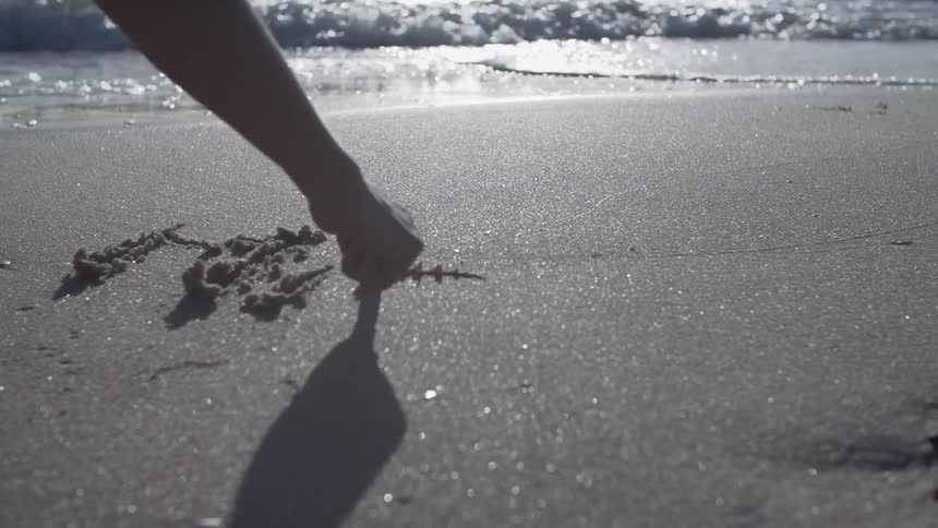 Person tracing words in the sand