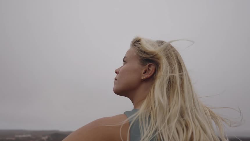 Woman standing on high ground overlooking the landscape under a cloudy sky