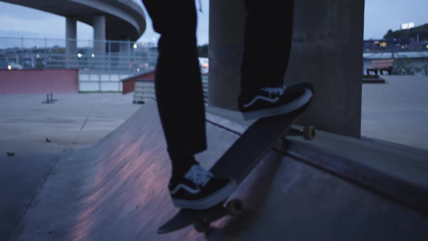 The video shows a closeup of a person skateboarding they are rolling down a small ramp or quarter pipe at an outdoor skate park